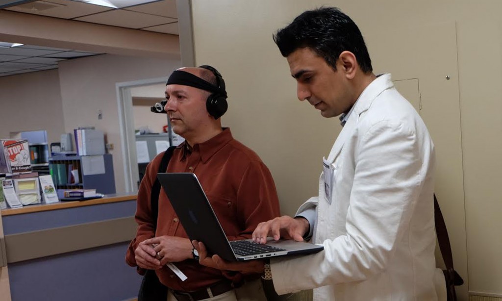 CSUN professor Hessam Ghamari (right) works with a volunteer (left) to explore neuro-imaging technologies that examine the environmental landmarks that draw in our eye and attention as we navigate a space. Photo courtesy of Hessam Ghamari.