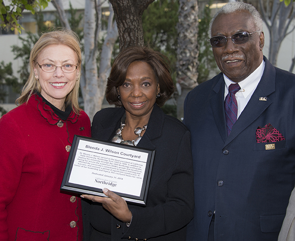 Blenda Wilson (center), CSUN's third president, accepts a gift from CSUN's current president, Dianne F. Harrison at the dedication of a courtyard in her honor. To Wilson's left is her husband, Louis Fair Jr. Photo by Lee Choo.