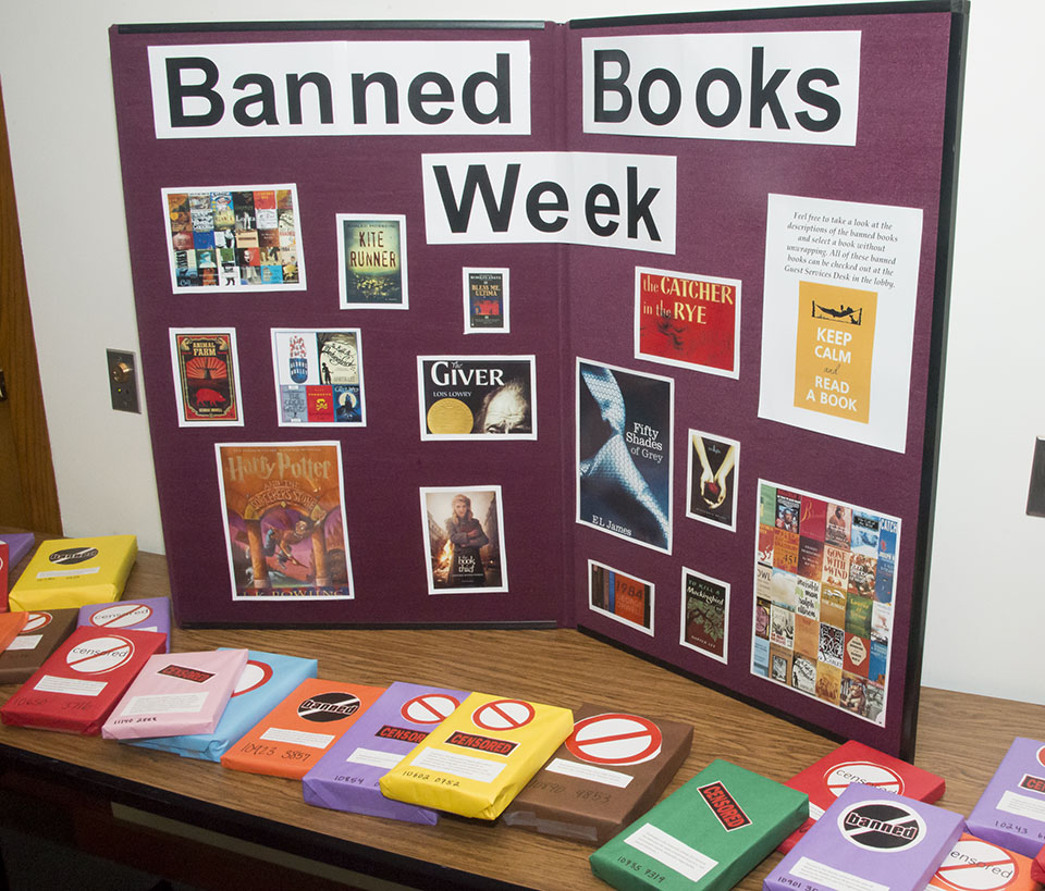 A large "Banned Books Week" poster display shows some of the books that have been banned in recent decades, including Harry Potter and The Catcher in the Rye.