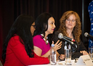 Rashmi Menon, Nury Martinez and Deanna Austin sit at a table on stage, while Martinez speaks into a microphone.