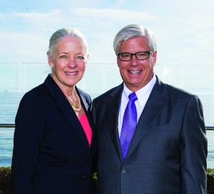 Alumni Janet Garufis and George Leis, colleagues at Montecito Bank & Trust, stand outside in front of an oceanfront view.