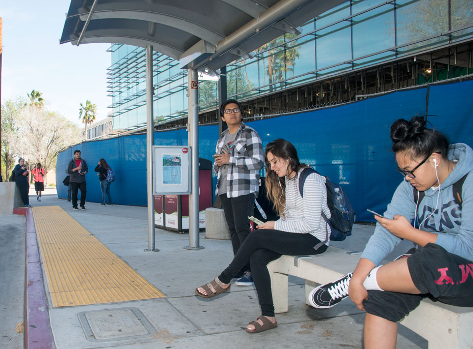 CSUN freshman Howard Sebastian (standing, center), a secondary education major, waits for a rapid bus line at the campus Transit Center. Sebastian commutes two hours to school from his home in East Los Angeles, several times a week. Photo by Lee Choo.