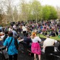 Musicians play on a stage in front of an audience that is seated on grass.