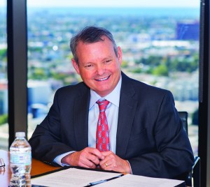 Alumnus Richard Schweitzer sits at a conference room table at his Aristotle Capital Management offices, with a view of Santa Monica and the ocean behind him.