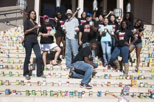 A group of students standing on library steps surrounded by canned food