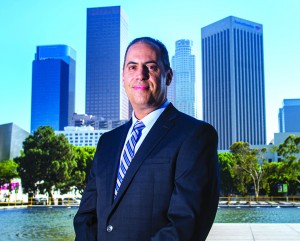 Alumnus Jeremy Wolfson stands in front of his LADWP office, in a plaza with the downtown Los Angeles skyline in the background.
