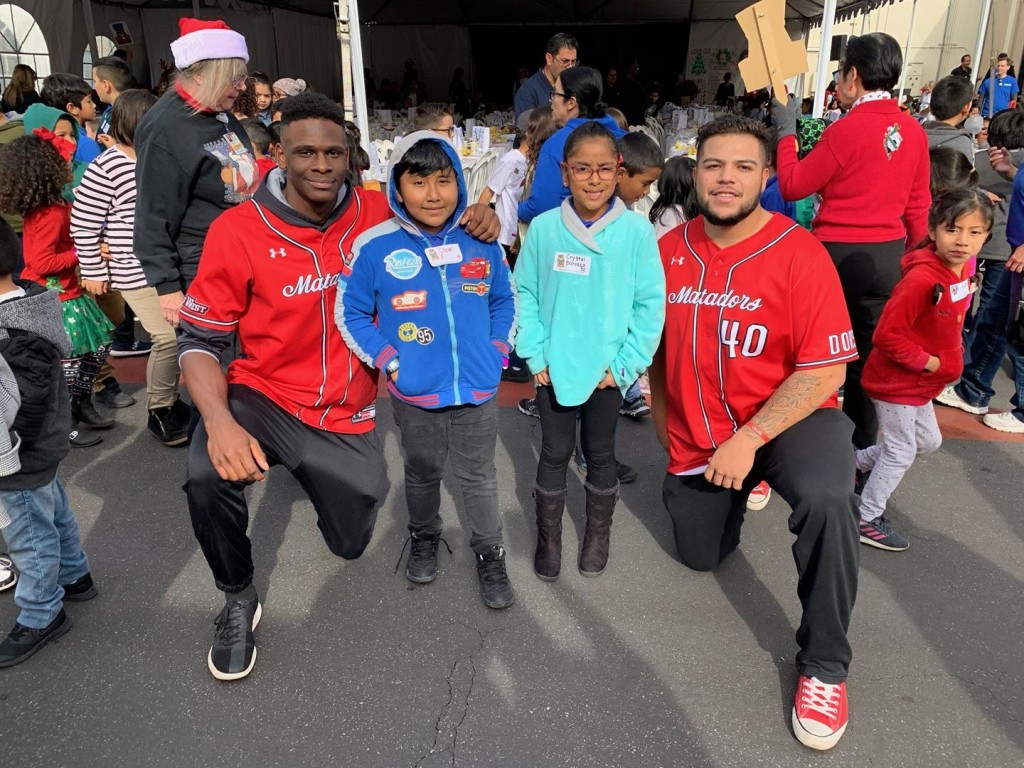 CSUN Baseball players Denzel Clark and Gabe Gonzalez pose with children 19th annual Dignity Health Northridge Hospital "Helping Hands Holiday Jam" Event for Children.