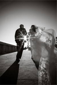 A bride and groom hold hands as they walk off into the sunset.