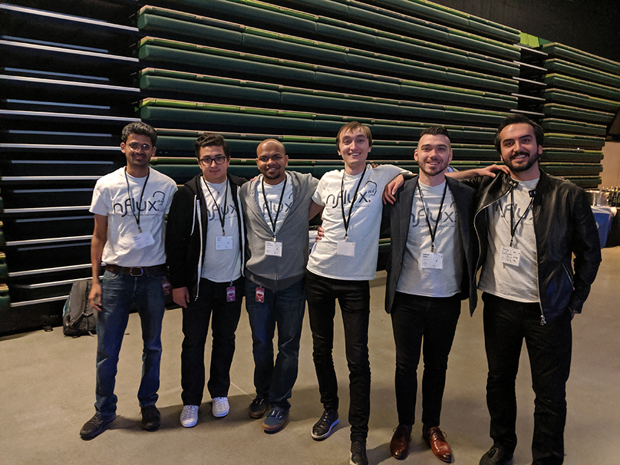 The nFlux team composed of six members wearing lanyards pose for a photo to celebrate their placement in the Amazon Alexa Accelerator.