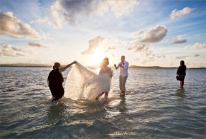 Groom beams as he is joined by his new bride in the ocean. Photo courtesy of Joe Buissink. 