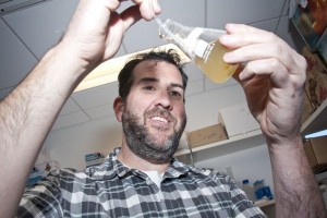 CSUN ecology professor Casey terHorst retrieves a sample of symbiotic algae from a test beaker in his lab. Photo by David J. Hawkins. 