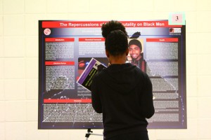 A student examines a research poster at the fall 2016 Men of Color Enquiry. Photo courtesy of Cedric Hackett. 