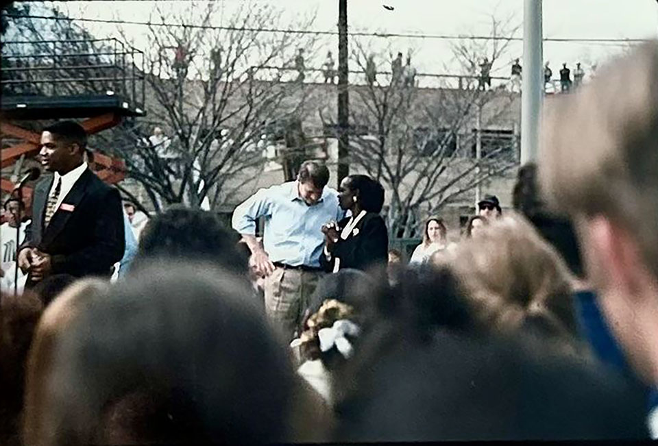 Alumnus Steven Parker, then Associated Students President, stands at a microphone, introducing Vice President Al Gore. CSUN President speaks to Gore in the background.
