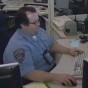 CSUN police dispatcher Tom Cavanaugh sitting at his desk at work.