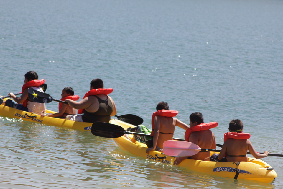 A group of children paddling kayaks.