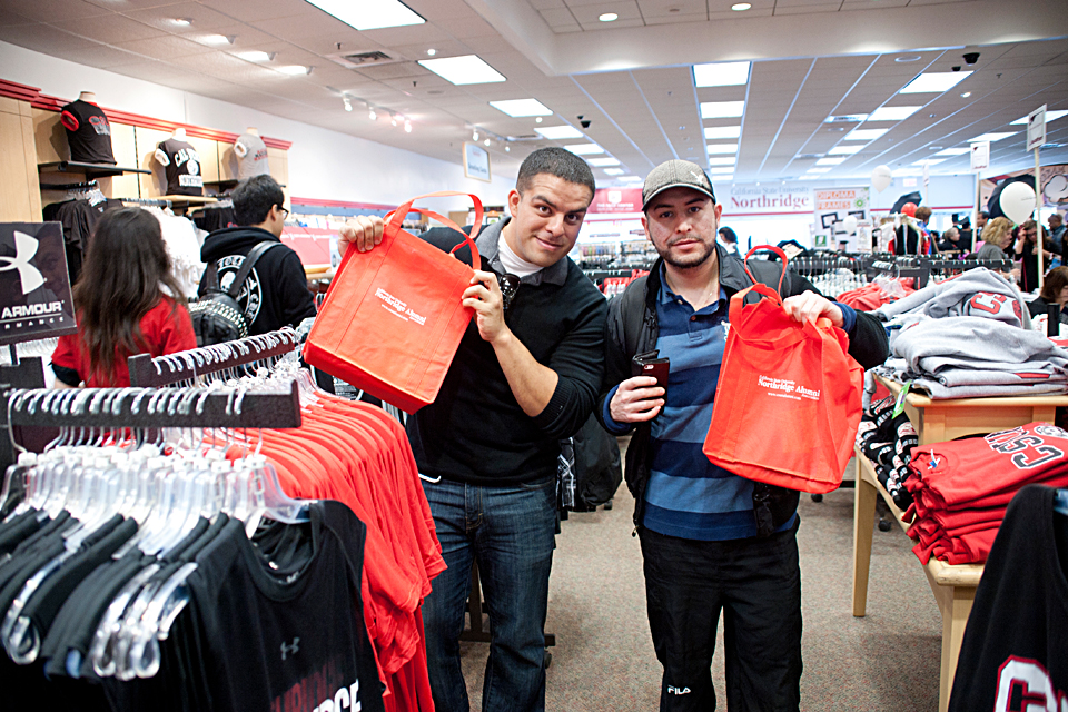Two male students pose with CSUN Alumni Association bags.