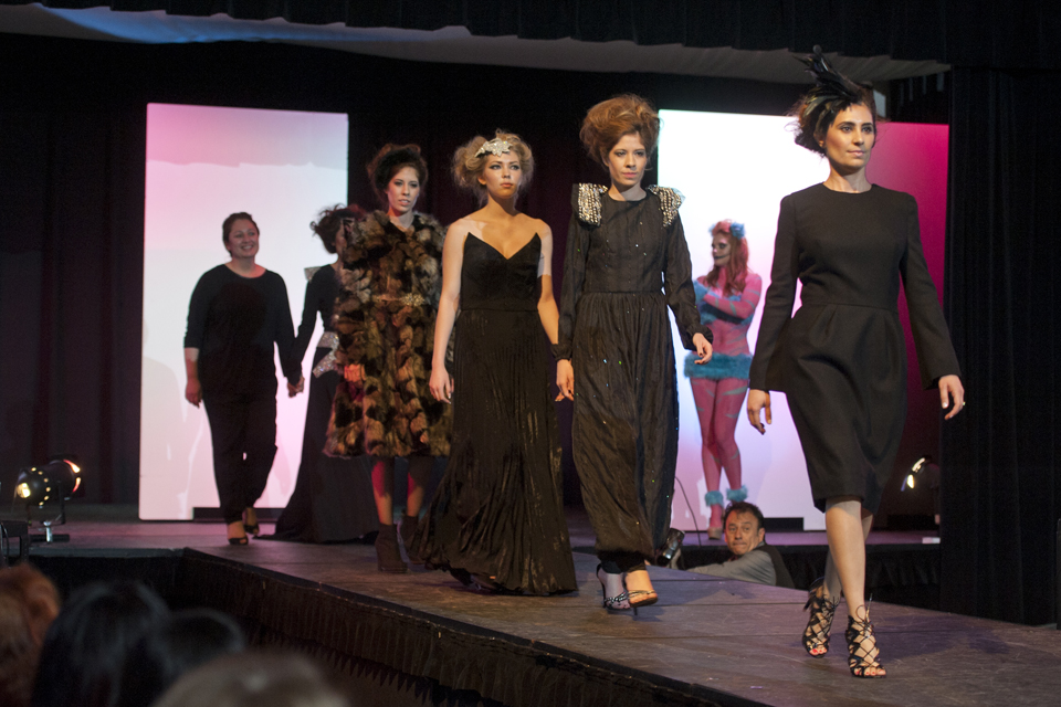 One of the student designers and models wearing her creations walk on the runway.