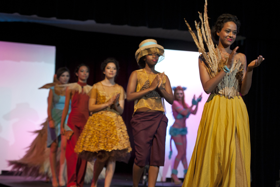 Models wearing outfits designed by the first place winner walk the runway.