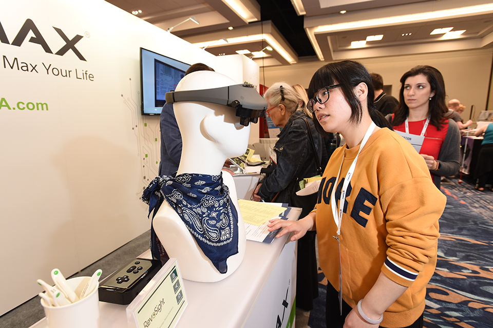 A woman inspects high-tech glasses on a mannequin head.