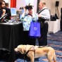 A woman with a service dog tries vision-enhancing glasses at the CSUN Conference.