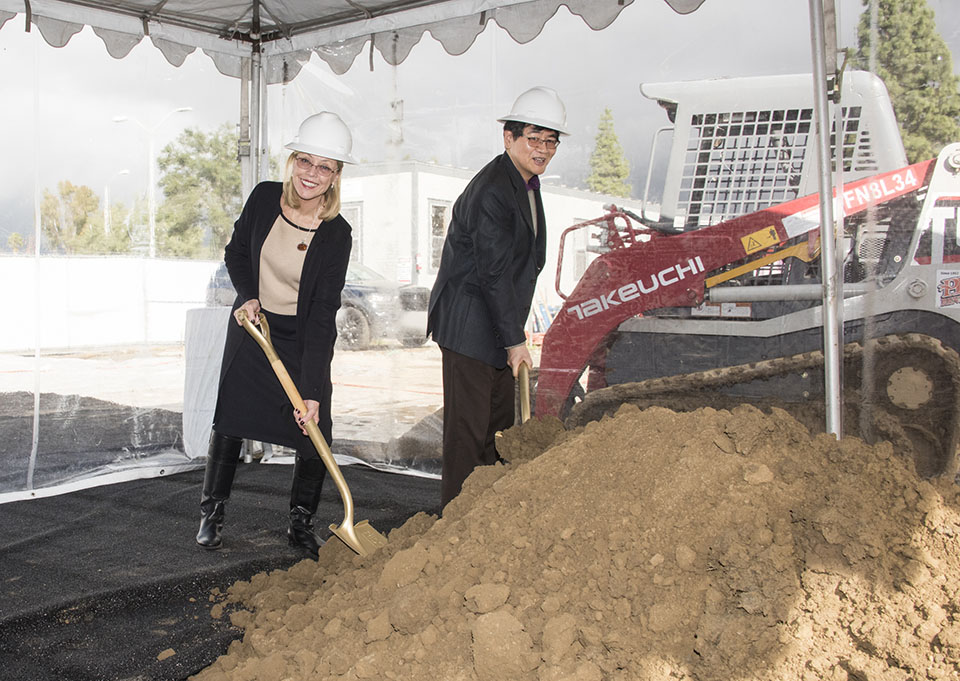 President Harrison and Provost Li wear hardhats and shovel dirt at research building groundbreaking.