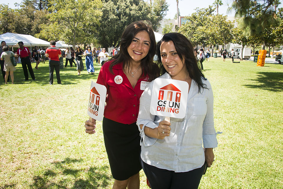 Two people carrying CSUN Dining signs at President's Picnic 2017.