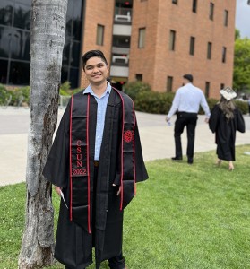 Aaron Nanas in graduation gown on CSUN campus.