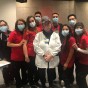 A group of CSUN students in masks and scrubs take a group photo after volunteering to assist with COVID-19 vaccinations.