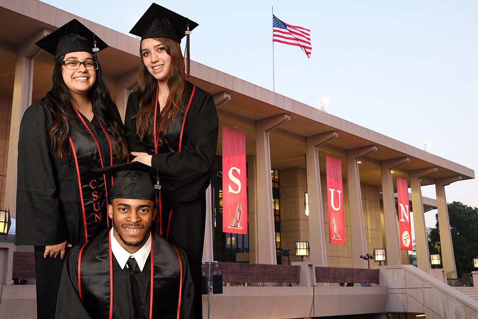 A Photoshopped group shot of three CSUN graduates in caps and gown in front of the CSUN Library virtual background.