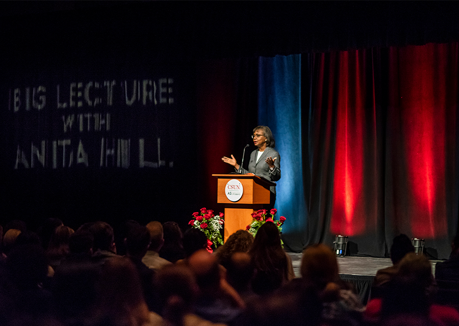 Anita Hill stands and speaks at a podium
