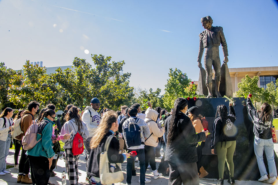 Students with roses approach the Matador statue.
