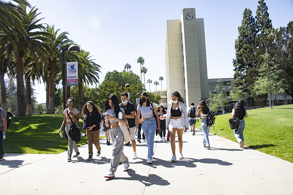 Students walk on sidewalk with Sierra Clock Tower in the background.
