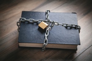 A black book with chains and a lock enclosing it.