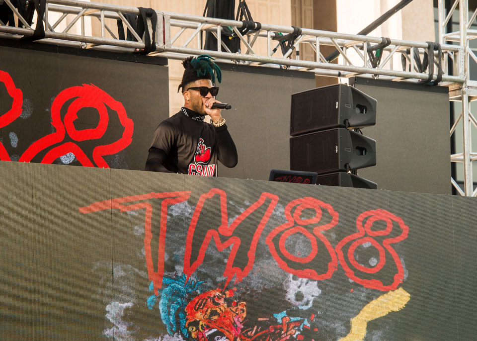 Hip hop DJ TM88 performing on stage in a CSUN shirt.