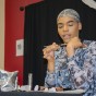 A person in a headscarf applies makeup to their first and blends it using a makeup brush.