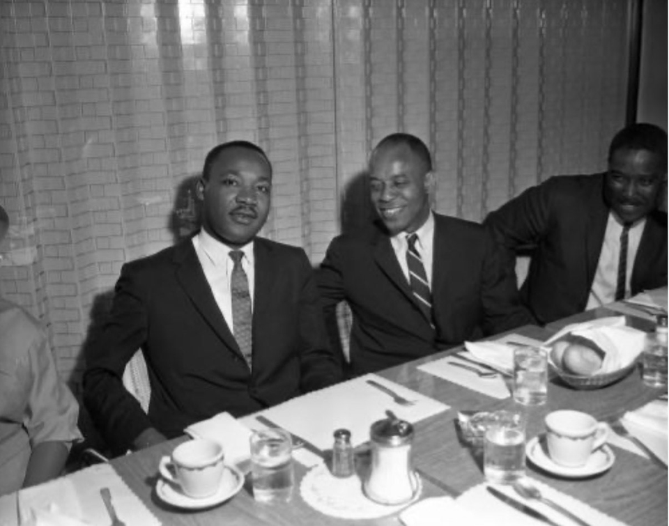 Martin Luther King, Jr. sits with two men at dining table.
