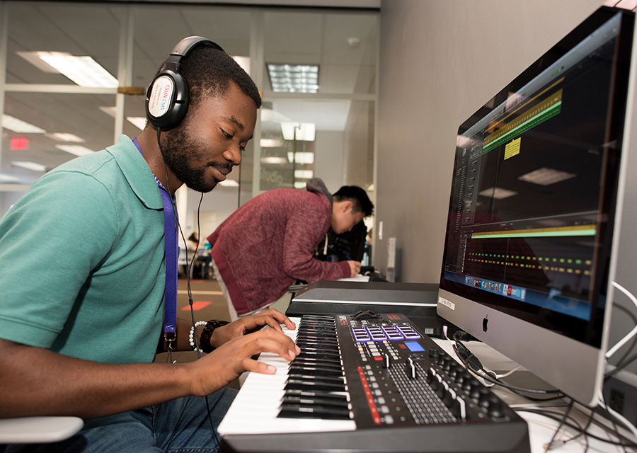 A student records music with a keyboard and software on a Mac computer at the Creative Media Studio.