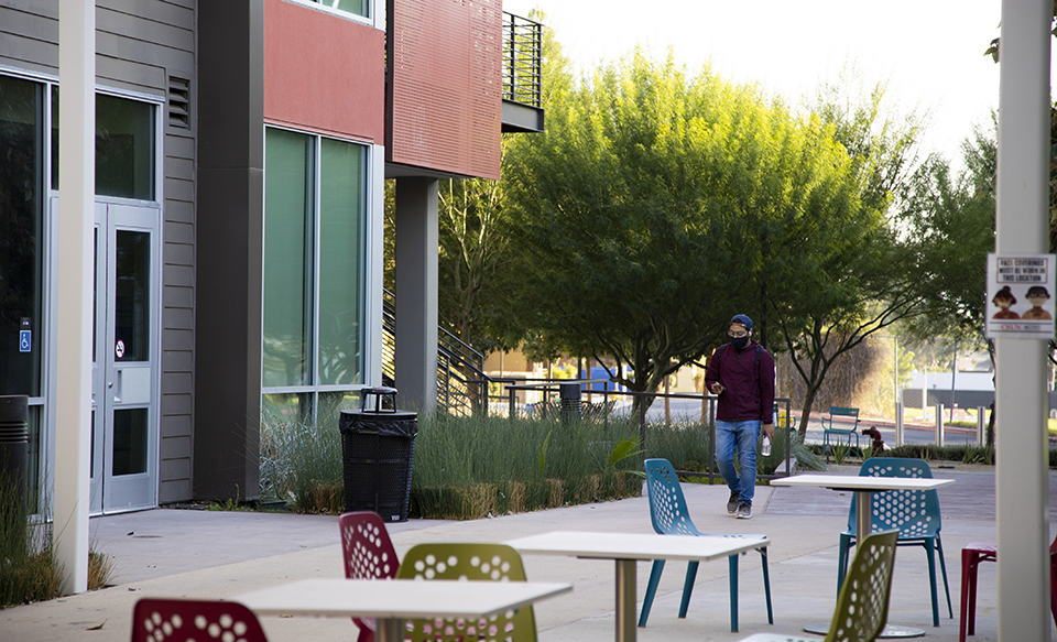 A masked student walks through the nearly empty CSUN Student Housing area.