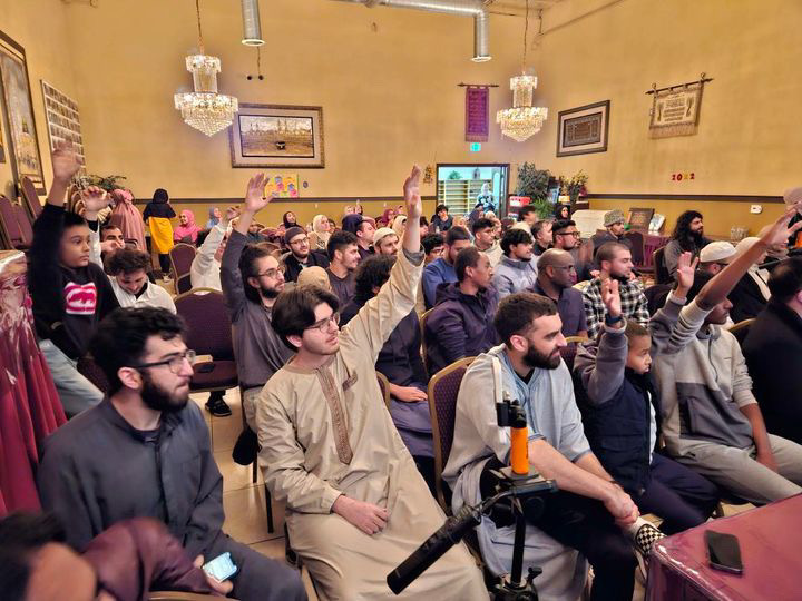 CSUN Muslim Student Association members raising their hands at a mosque.