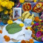 Red and yellow flowers, cactus leaves, bananas and colorful patterned fabric decorate an altar.