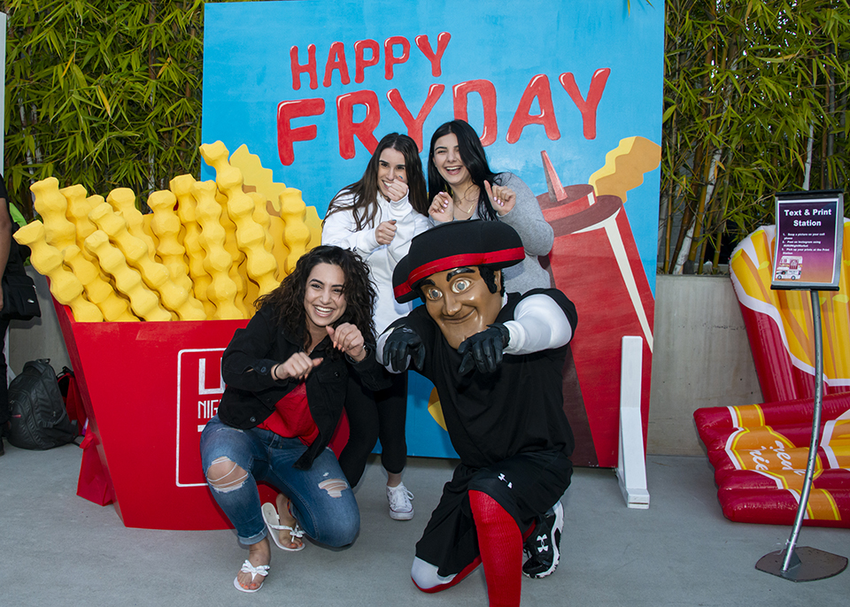 Matty the matador and three female students posing by life-size fries.