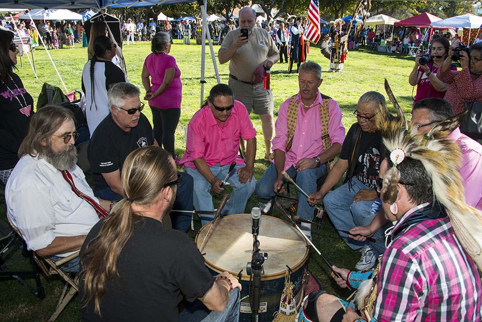 American Indian men sitting around a drum playing and singing.