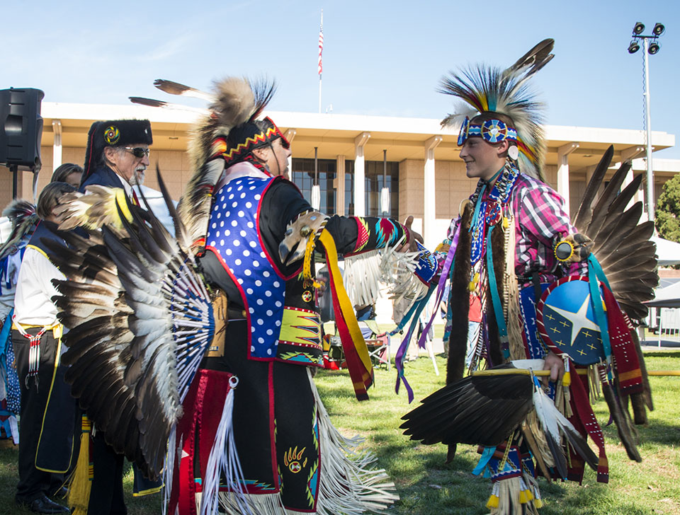 American Indian boy dancer shaking hands with other dancer.