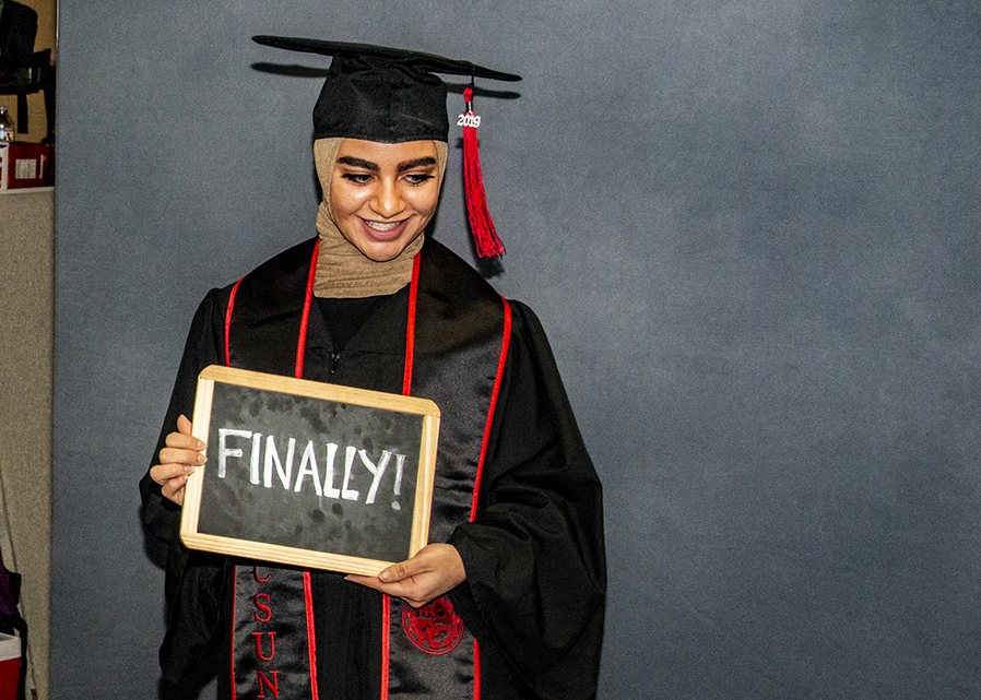 Young woman in a Hijab, in cap and gown, holding a 