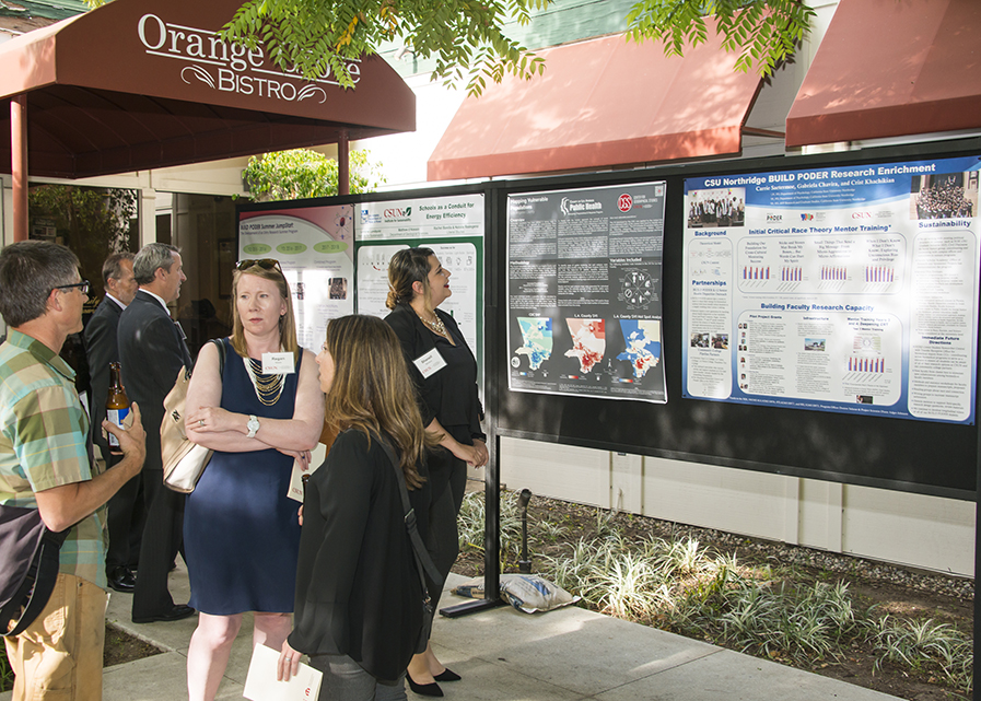 A group of CSUN faculty converse near a series of research posters at the Orange Grove Bistro.