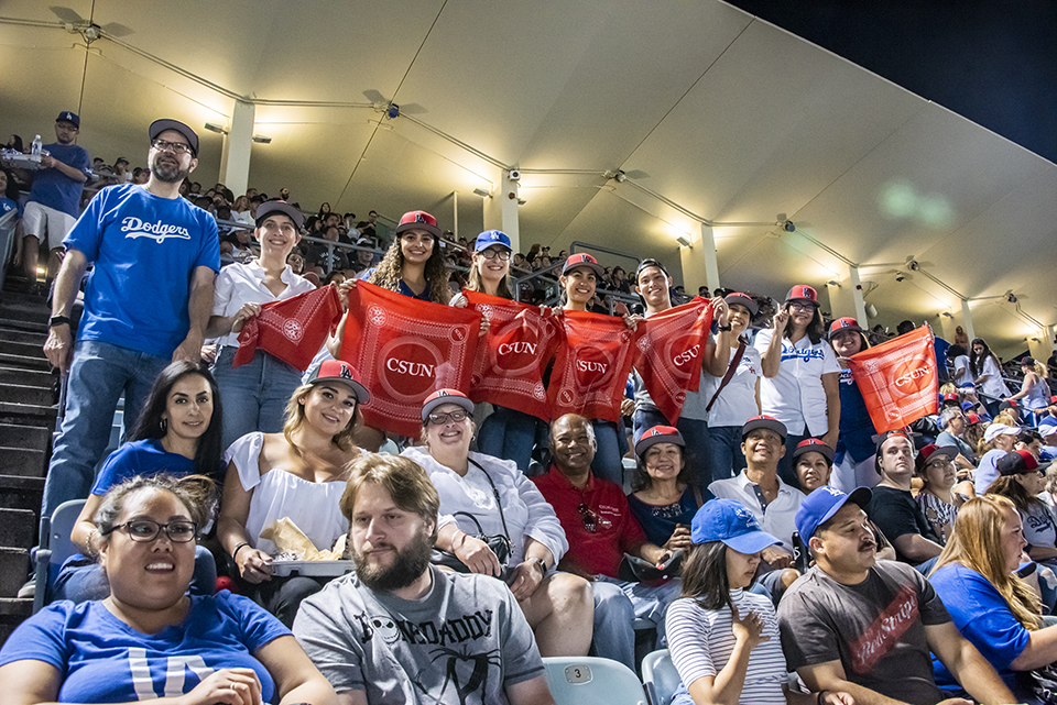 A group of CSUN staff and alumni hold up CSUN scarves in the stands at Dodger Stadium.