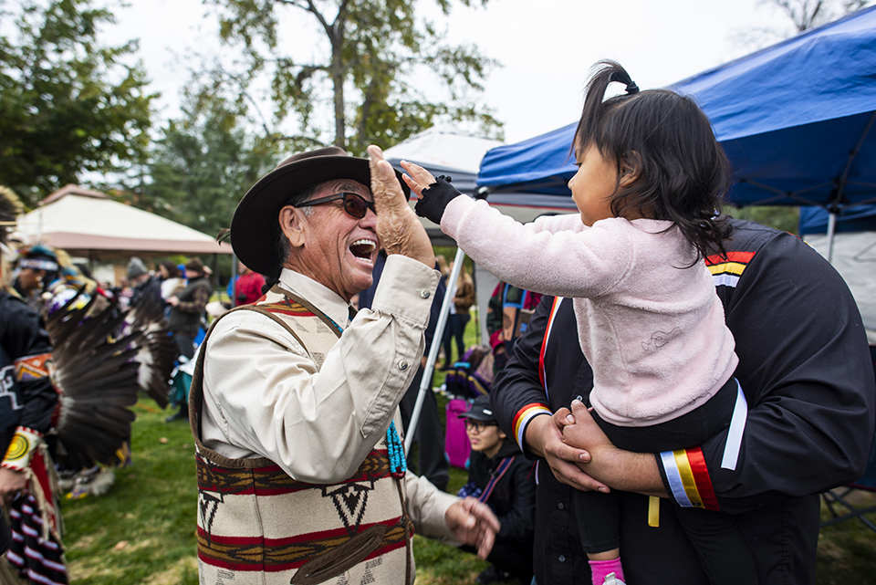 A man happily high-fives a little girl at the 2019 CSUN Powwow.