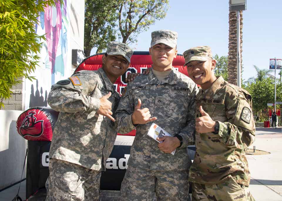 Student veterans make hand gestures for a picture on the CSUN Plaza del Sol.
