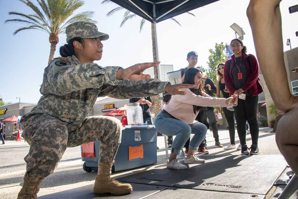 A CSUN student tries to hang with a student veteran in a squat exercise.