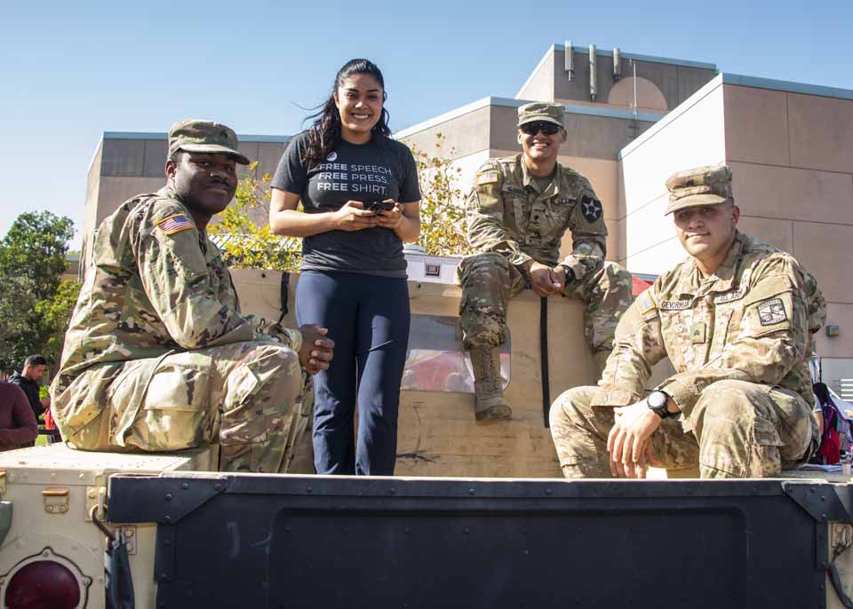 A CSUN student poses with veterans on the back of a Humvee.
